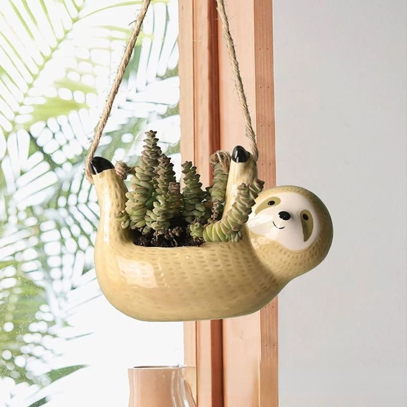 Ceramic sloth hanging flowerpot with hemp rope; whimsical design in blue, grey, or khaki, perfect for home decor.