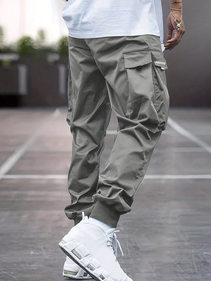 "Durable men's black cargo pants front view with multiple pockets, sleek modern fit, versatile style for urban adventures."