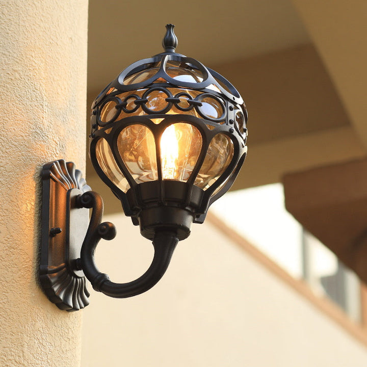 "Elegant bronze/black outdoor wall light with matte finish, transparent globe shade, perfect for garden or porch lighting."