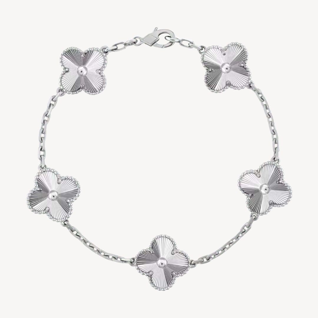 Elegant clover charm bracelet with polished black agate inlays and a gold and silver-tone chain for sophisticated style.