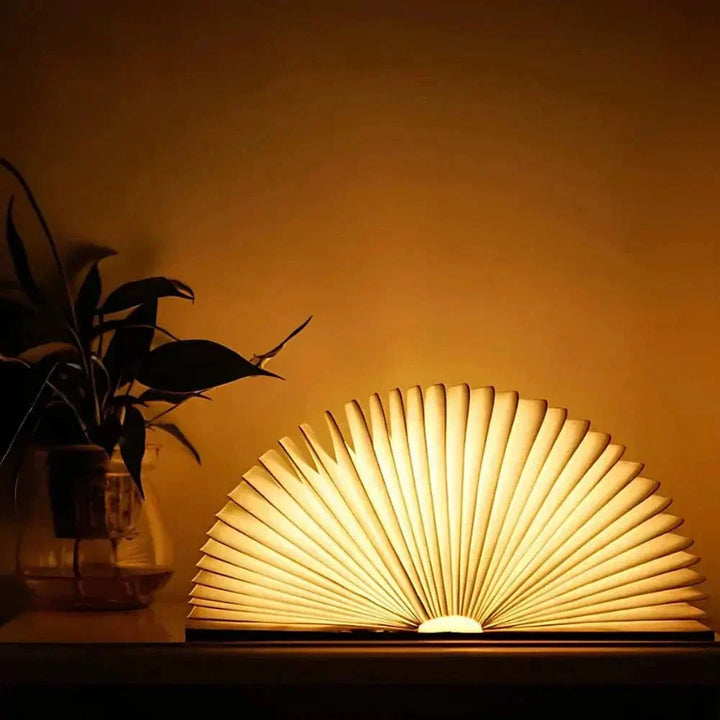 "Elegant foldable LED book lamp, warm white light, 360-degree design, portable for home or travel, wood and paper material."