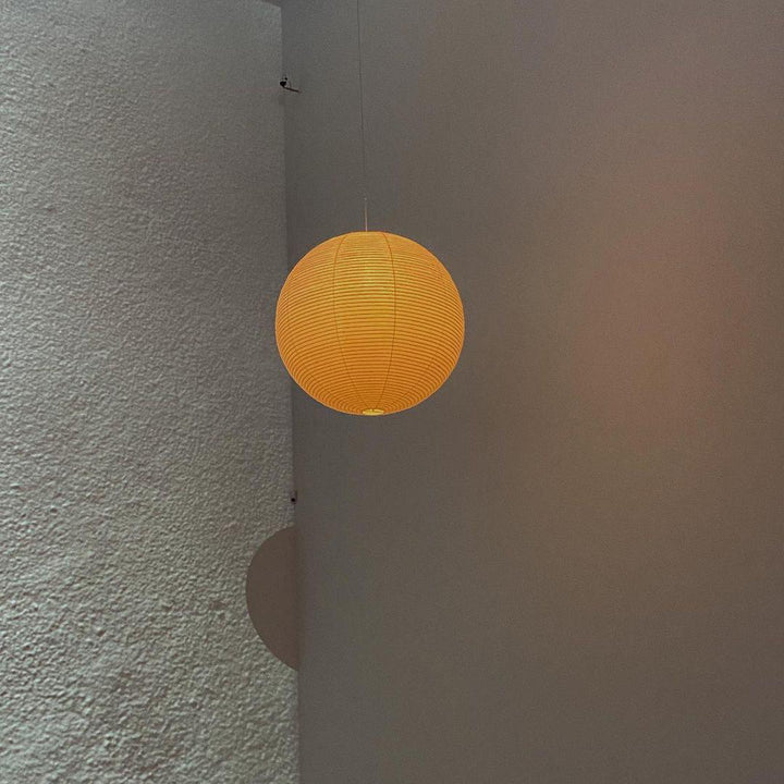 "Elegant modern Japanese paper lantern pendant light with a warm glow, blending contemporary and mid-century design."