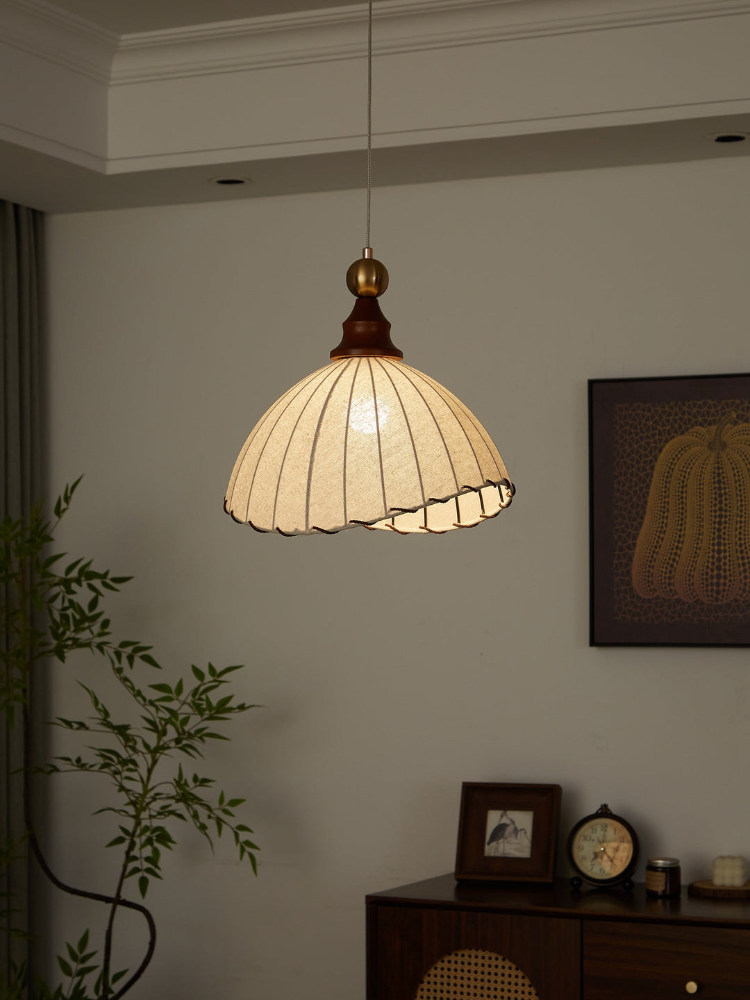 Elegant pendant light with pleated fabric shade, gold-finished top, and wood accent; perfect for modern interiors.