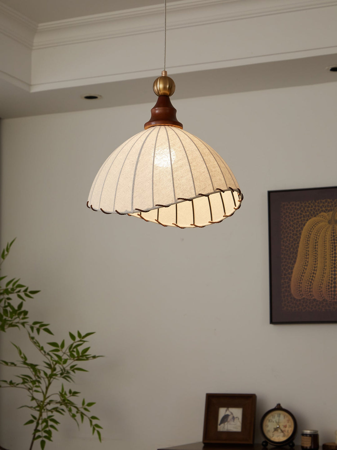 Elegant pendant light with pleated fabric shade, gold-finished top, and wood accent; perfect for modern interiors.