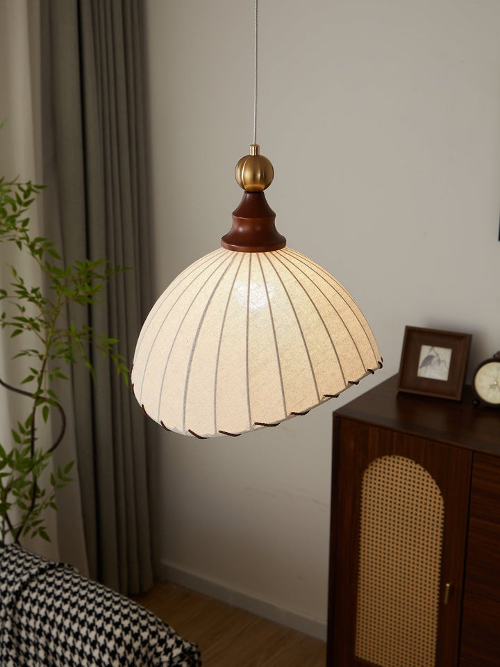 Elegant pendant light with pleated fabric shade, gold-finished top, and wood accent; perfect for modern interiors.