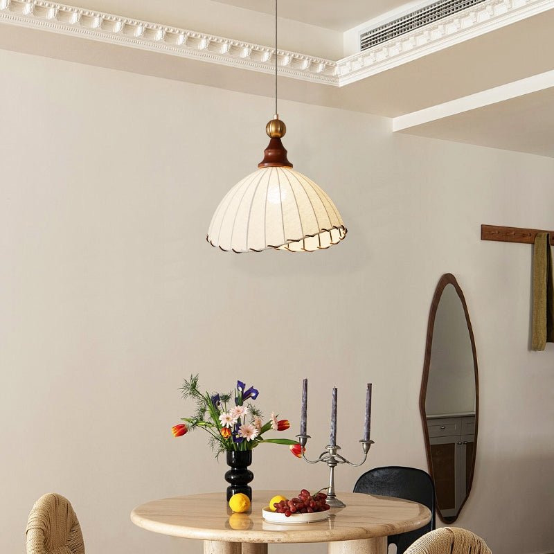 Elegant pendant light with pleated fabric shade, gold-finished top, and wood accent; perfect for modern interiors.