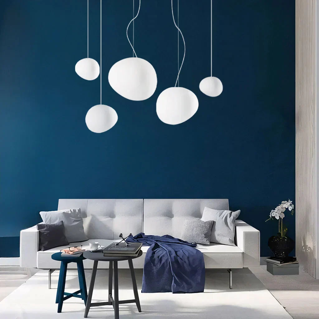 Elegant white pebble pendant light; minimal design, frosted glass, metal accents, soft glow for modern interiors.