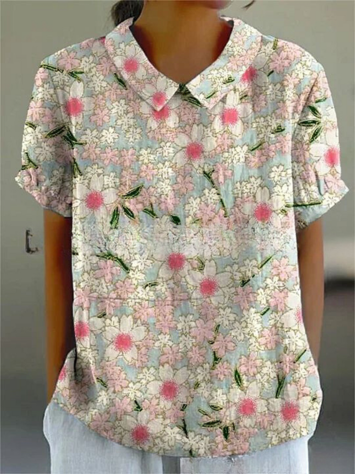 Full length view of a women's elegant floral blouse with Peter Pan collar, short sleeves, and vibrant print.