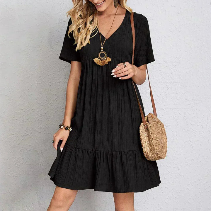 Detail shot of the flattering waistline and flowy skirt of an elegant V-neck midi summer dress for women.