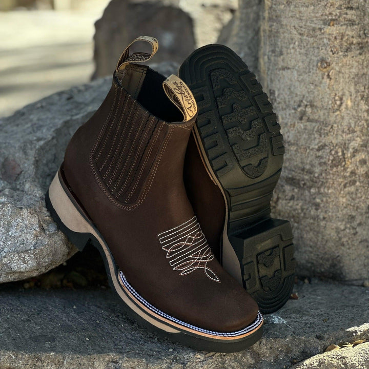 Men's western cowboy boots with intricate embroidery, squared toe & elastic sides for easy pull-on. Rugged casual style.