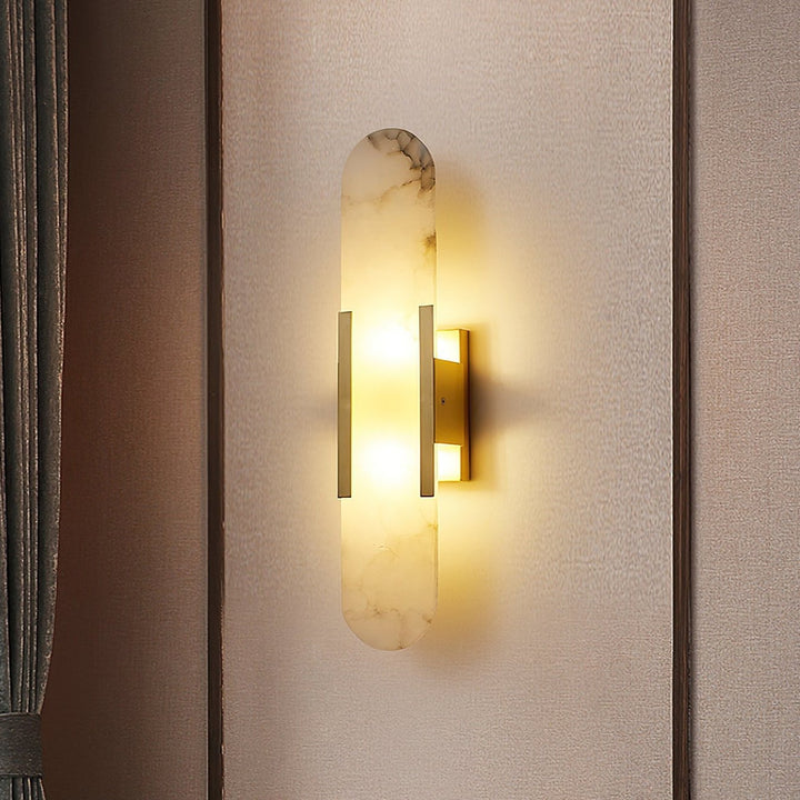 "Modern elongated alabaster wall lamp with metal and brass accents, emits warm glow, suitable for chic interior decor."