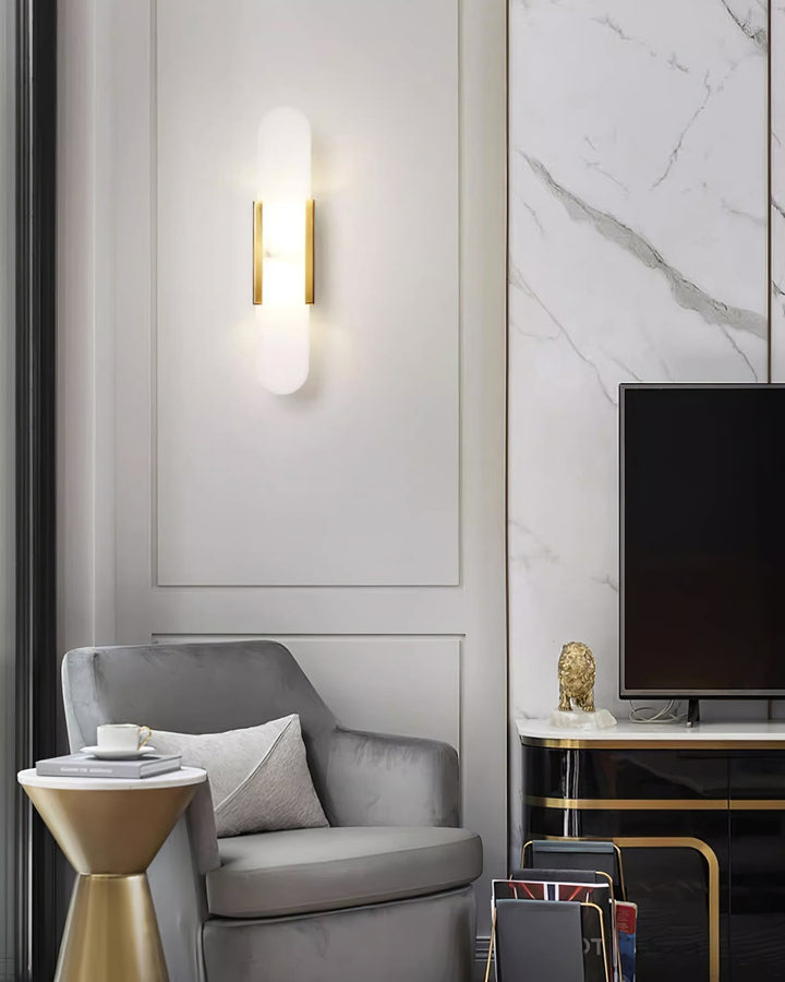 "Modern elongated alabaster wall lamp with metal and brass accents, emits warm glow, suitable for chic interior decor."