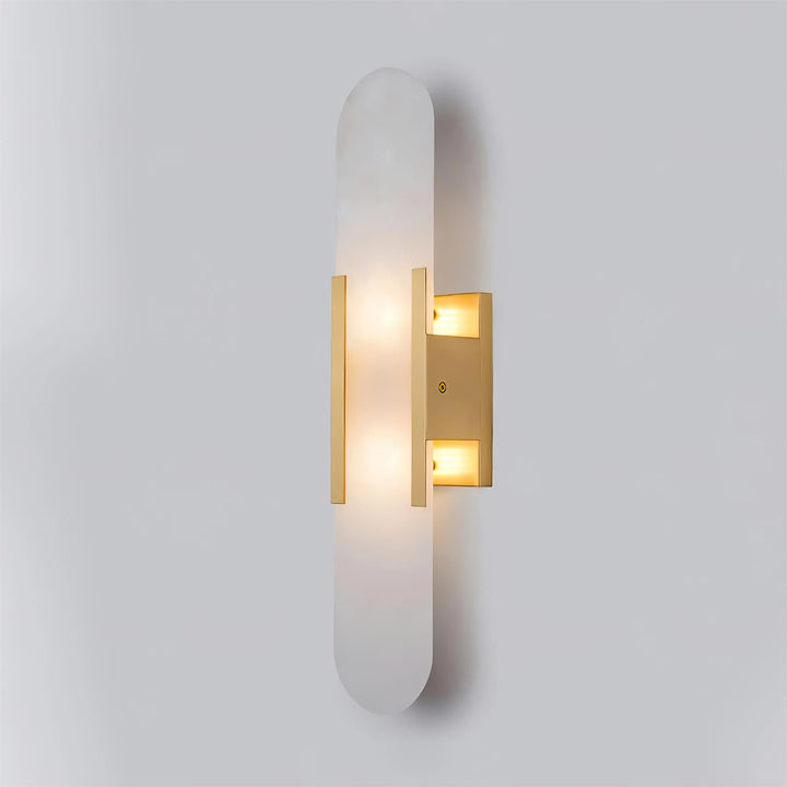 "Modern elongated alabaster wall lamp with metal and brass accents, emits warm glow, suitable for chic interior decor."