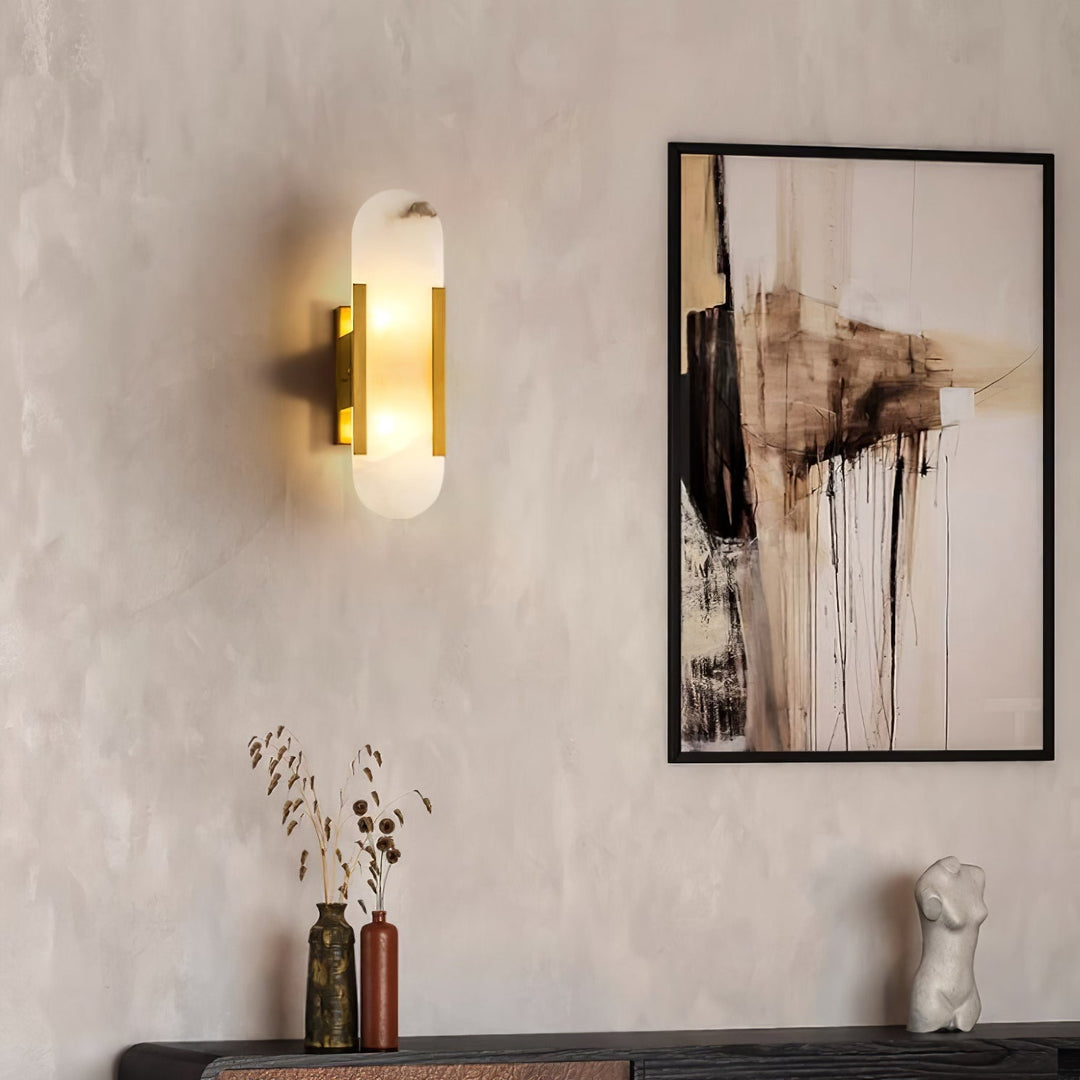 "Modern elongated alabaster wall lamp with metal and brass accents, emits warm glow, suitable for chic interior decor."