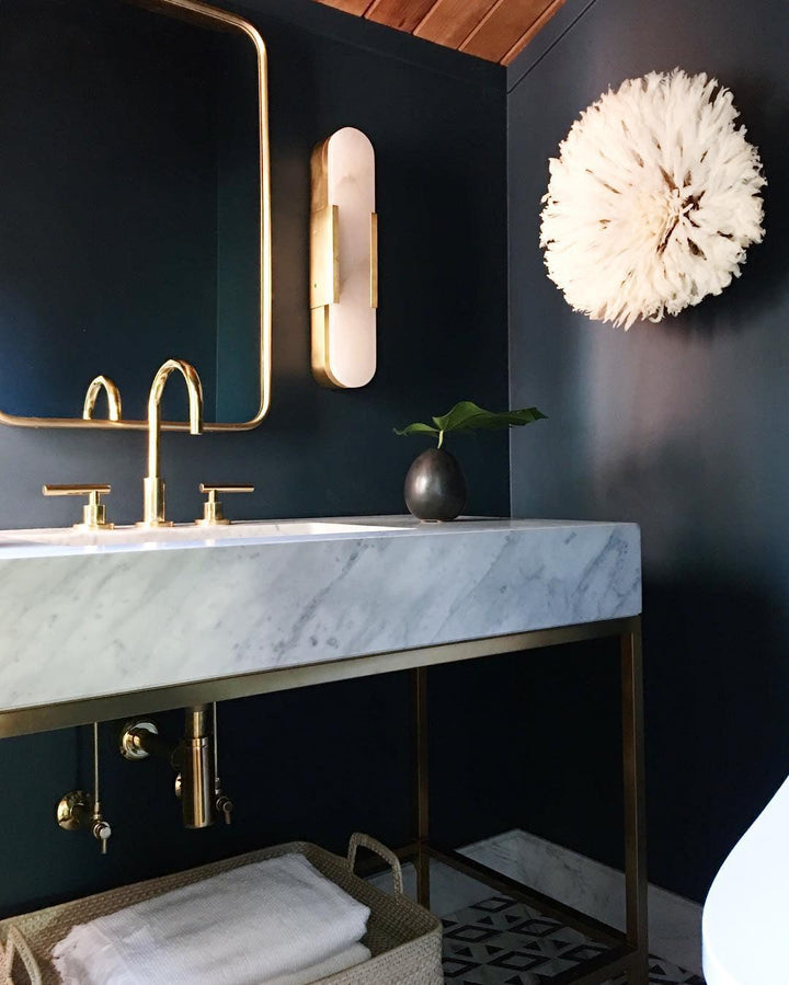 "Modern elongated alabaster wall lamp with metal and brass accents, emits warm glow, suitable for chic interior decor."
