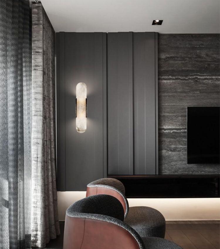 "Modern elongated alabaster wall lamp with metal and brass accents, emits warm glow, suitable for chic interior decor."