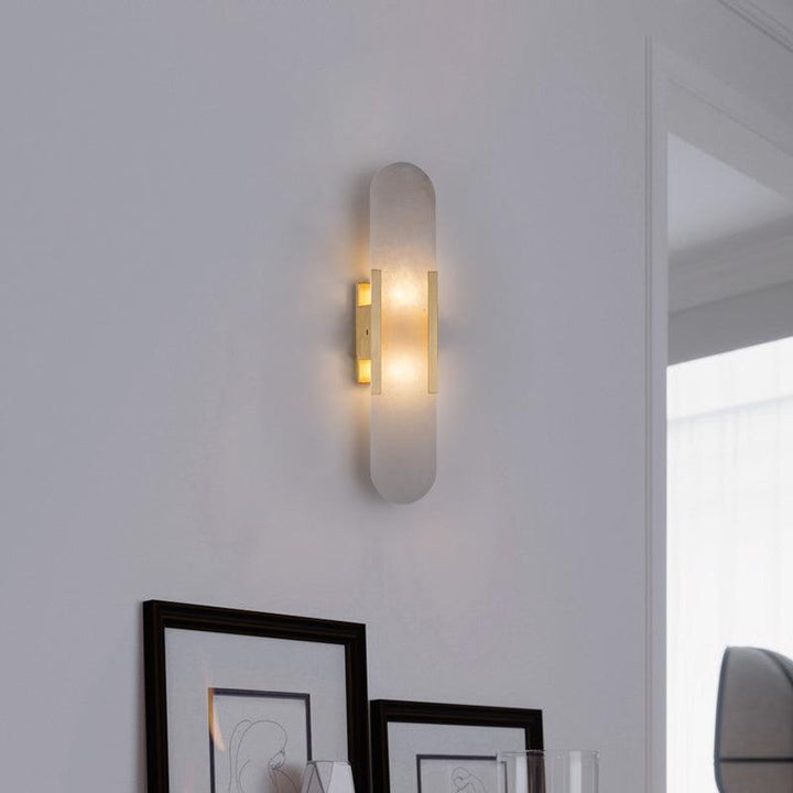 "Modern elongated alabaster wall lamp with metal and brass accents, emits warm glow, suitable for chic interior decor."