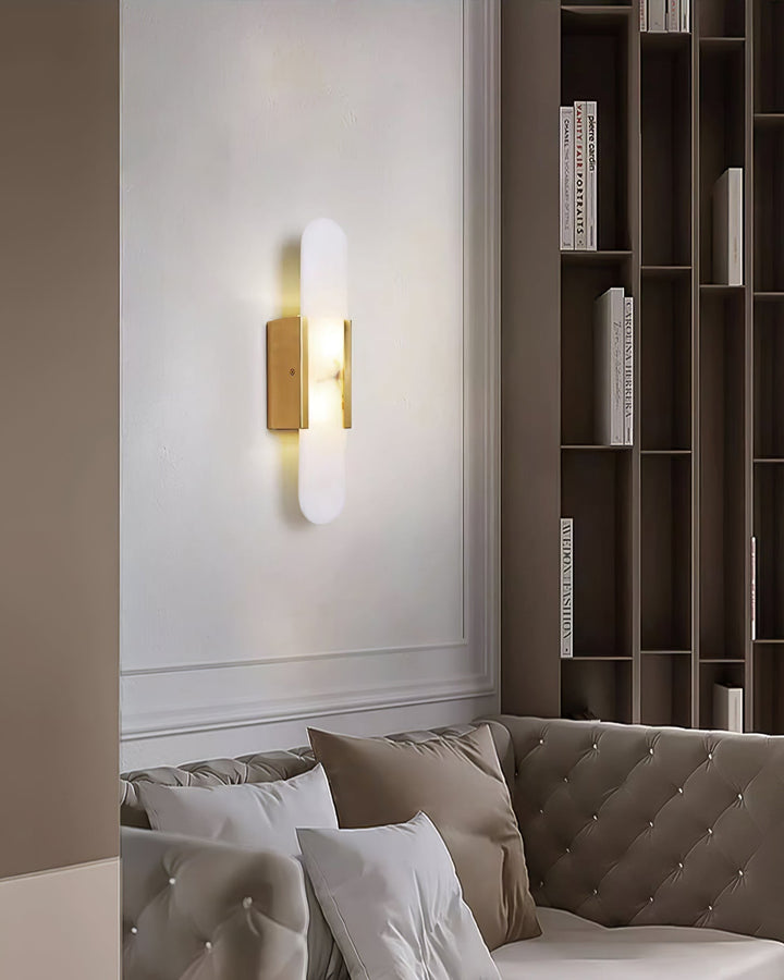 "Modern elongated alabaster wall lamp with metal and brass accents, emits warm glow, suitable for chic interior decor."