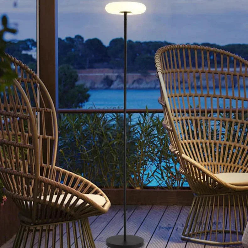 Outdoor solar floor lamp with metal and acrylic body, modern design, stands on patio illuminating with warm LED glow.