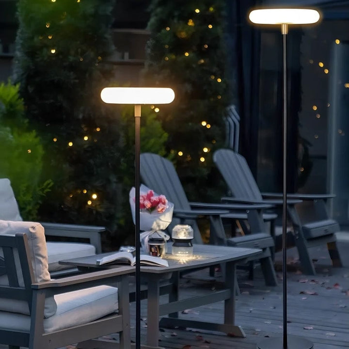 Outdoor solar floor lamp with metal and acrylic body, modern design, stands on patio illuminating with warm LED glow.