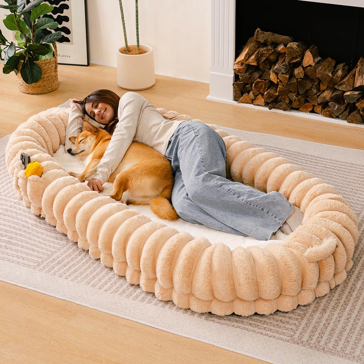 Ultra-soft large plush donut pet bed, creamy faux fur with bolsters for head support, fits humans and dogs, cozy design.