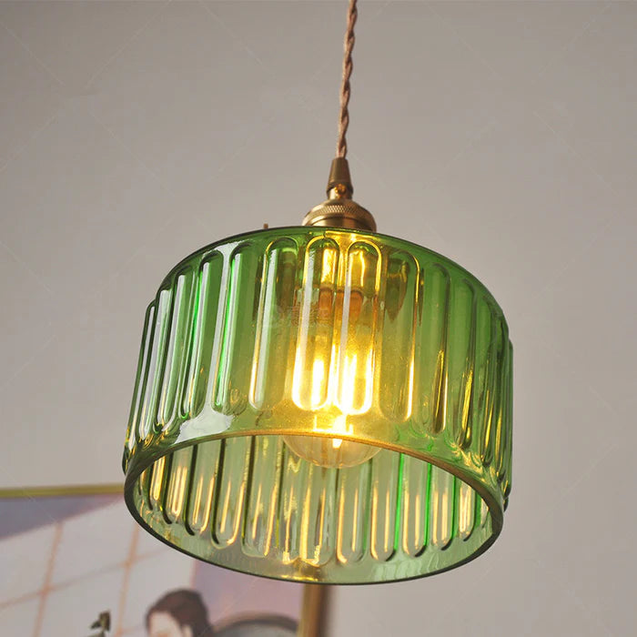 Vintage cylindrical glass pendant lamp casting warm glow; elegant centerpiece for home decor. Perfect for living and dining a