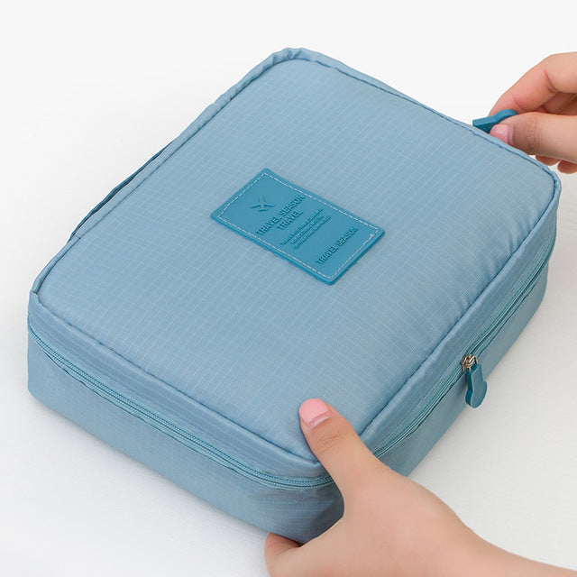Women's compact waterproof makeup bag filled with essential travel toiletries and cosmetics.