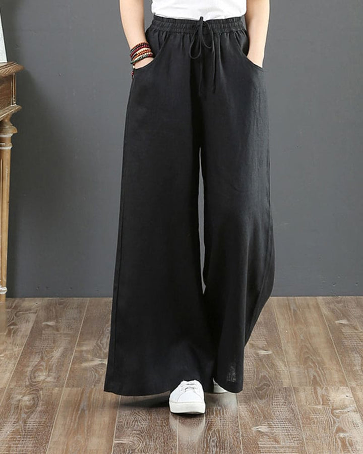 Woman wearing fashionable wide leg drawstring trousers, showcasing flowy fabric & comfortable, loose fit.