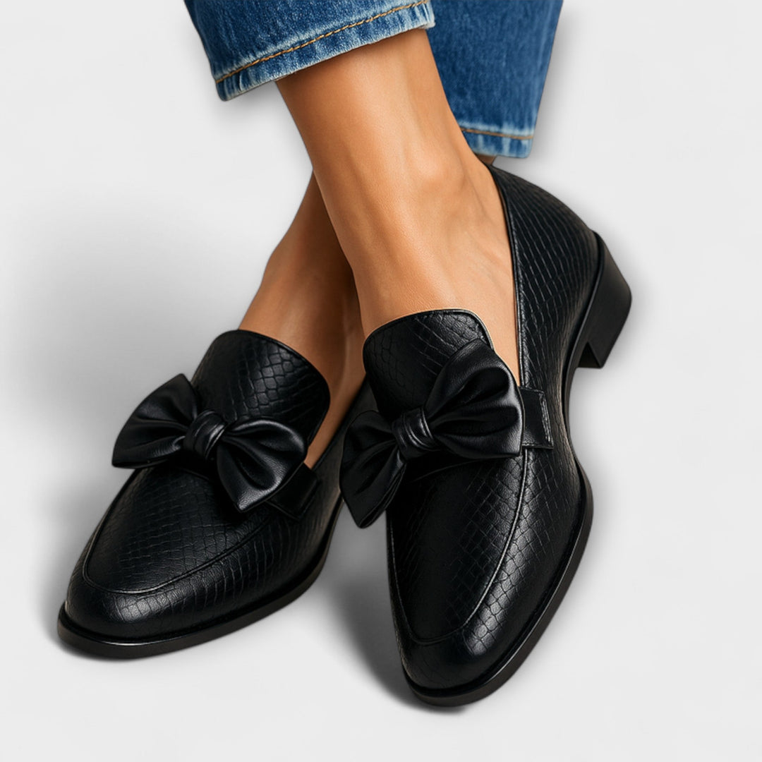 Women's elegant black slip-on loafers with a stylish bow, perfect for comfortable everyday wear or walking.