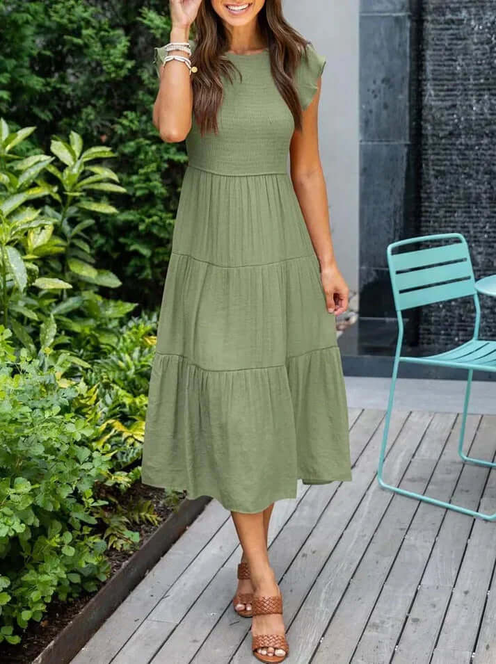 Full shot of a model wearing a chic pleated A-line midi dress with charming flutter sleeves, great for any occasion.