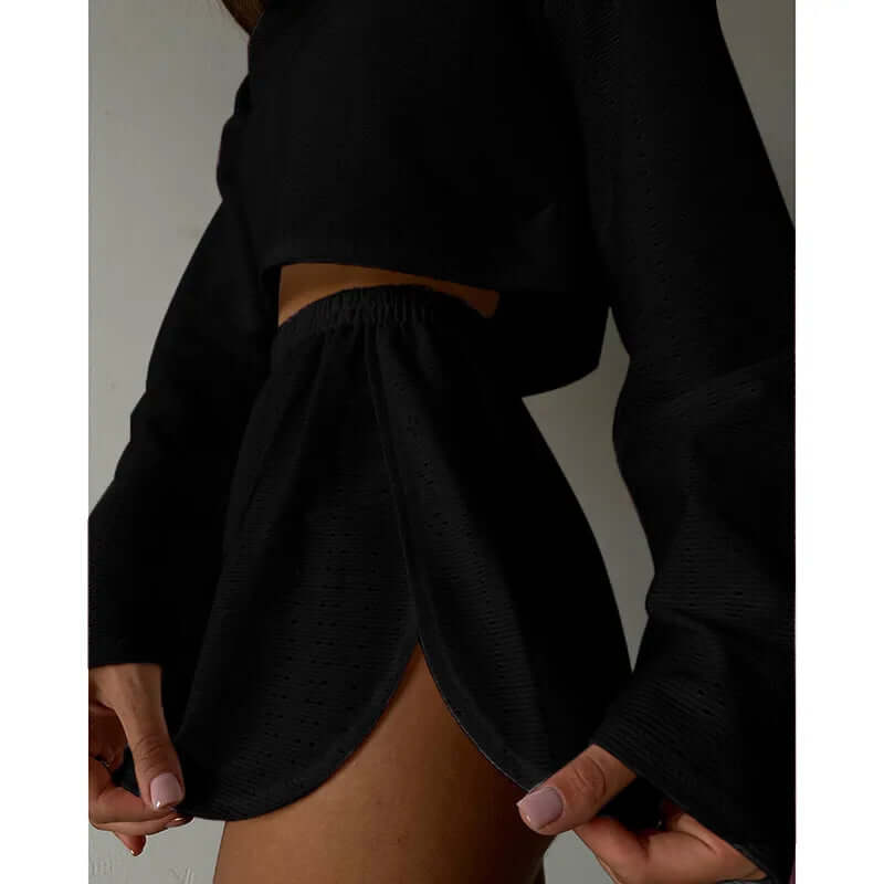 Woman in a comfortable eyelet knit lounge set, crop top and high-waisted shorts, relaxing at home.
