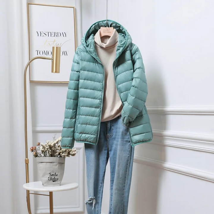 Folded ultralight women's hooded puffer jacket, compact & ready for travel essentials.
